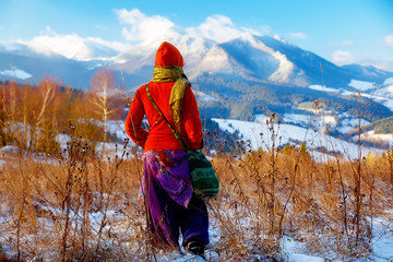 Canvas Print - girl in colorful ethno dress standing amids winter landscape.