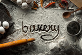 Fototapeta  - Word bakery is written on flour on cooking background. top view
