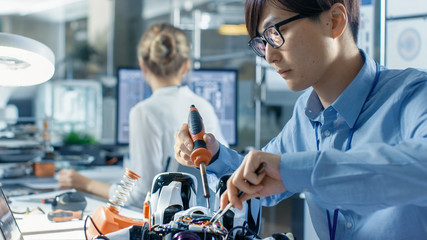 Wall Mural - electronics engineer works with robot, soldering wires and circuits. computer science research labor