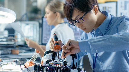 Wall Mural - electronics engineer works with robot, soldering wires and circuits. computer science research labor