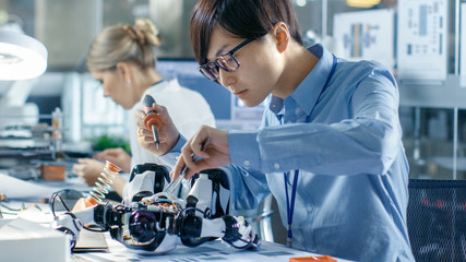 Wall Mural - electronics engineer works with robot, soldering wires and circuits. computer science research labor
