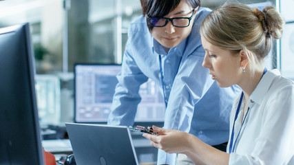 Wall Mural - female computer scientists connects circuit board to her laptop and starts programming it. she works