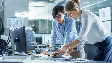 Wall Mural - two computer engineers choose printed circuit boards to work with. in the background technologically