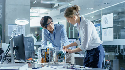 Wall Mural - two computer engineers choose printed circuit boards to work with. in the background technologically