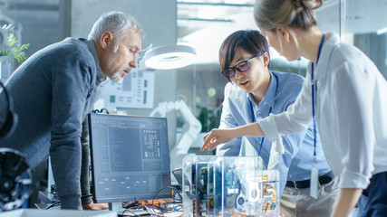 Wall Mural - team of computer engineers choose printed circuit boards to work with, computer shows programming in