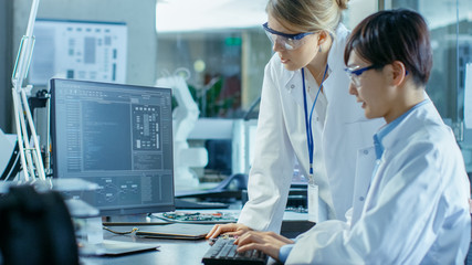 Wall Mural - two prominent computer engineers working with programming software on personal computer. in the back