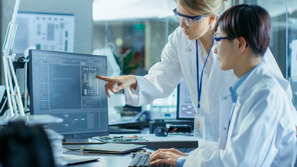 Wall Mural - two prominent computer engineers working with programming software on personal computer. in the back