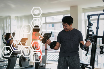 asian young handsome man powerful shouting screaming and doing exercise with dumbbell at biceps in fitness gym with graphic icon diagram, bodybuilder, healthy, workout and sport training concept