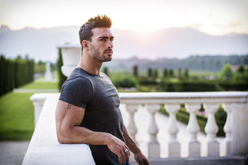 Handsome muscular man with tattoo posing in European luxury garden in Turin, Italy