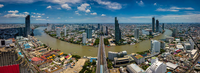 Fototapete - Aerial view of Bangkok skyline and skyscraper with BTS skytrain Bangkok downtown. Panorama of Sathorn and Silom business district Bangkok Thailand with blue sky and clouds.