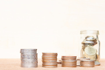 Wall Mural - Glass of coin and four pole range of coins on vintage blurred background - Saving money concept.