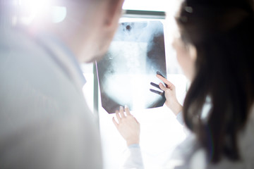 Wall Mural - X-ray image held by one of radiologists showing and explaining it to colleague