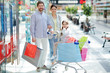 © pressmaster - Happy little girl in shopping cart and her parents enjoying weekend in large trade center