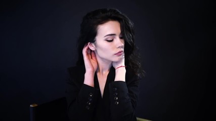 Wall Mural - Sensual portrait of beautiful woman with curly hair in dark clothes posing on black background in studio