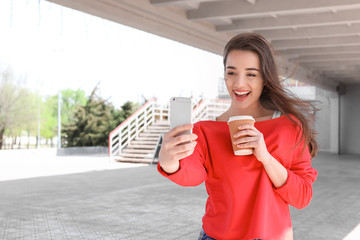 Wall Mural - Attractive young woman taking selfie with phone outdoors