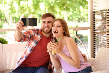 Canvas Print - Happy young couple taking selfie in cafe on spring day