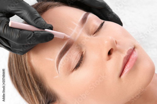 Young woman undergoing eyebrow correction procedure in salon Tapéta, Fotótapéta