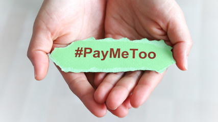 Wall Mural - #PayMeToo as a new social movement. A piece of paper with #PayMeToo written on the palm of a woman's hand.