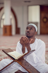 Wall Mural - Black African Muslim Man Is Praying In The Mosque with open holy book of Koran