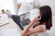 © weedezign - Asian female freelancer talk on mobile and see business graph on laptop screen with rest leg on table in bedroom at home.Work at home concept.work from home concept.