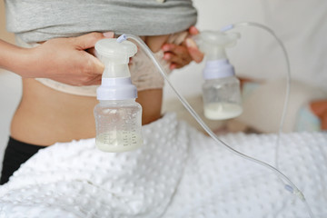 Mothers breasts milk for newborn baby in bed room at home.