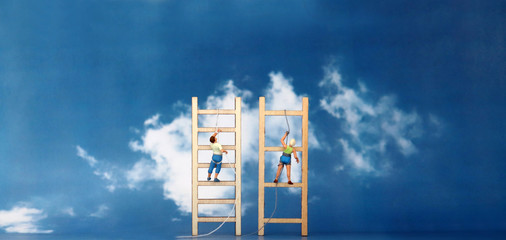 Miniature climbers climbing a wooden ladder against the backdrop of the blue sky. The concept of gender discrimination in employment and promotion.