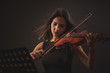 Pretty young woman playing a violin over black background