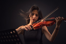 Pretty Young Woman Playing A Violin Over Black Background