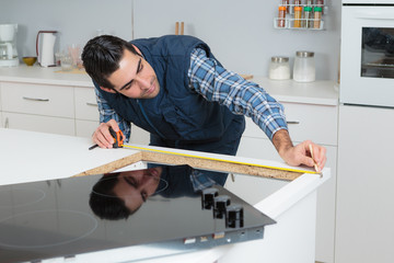 Man measuring worktop for installation of hob