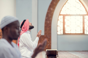 Two religious muslim man praying together inside the mosque