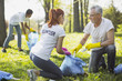© zinkevych - Non profit volunteer. Vigorous two volunteers holding garbage bag and chatting