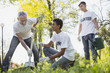 © zinkevych - Environmental organization. Low angle of vigorous three volunteers planting tree and grinning