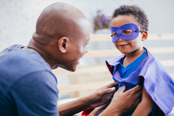 Happy smiling African American son being supported and helped by supportive father for little adventure and protection