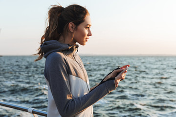 Wall Mural - Pretty young sportswoman holding mobile phone