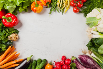 Stone background with a border of fresh vegetables.