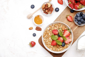 Wall Mural - Serving option of granola bowl with mix of nuts, cereals, fruits and berries, greek yogurt. Healthy vegetarian breakfast, organic strawberry, blueberry, mint, almond. Close up, top view, background.