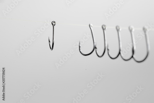 Fotografía Hooked hooks with white ropes hang many of them on a white backg