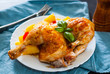 roasted half chicken with carrots, onions and potatoes served on a white plate on table