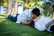 © Chayanin Wongpracha - A pair of lovers in the park with man kissing young woman on the grass.