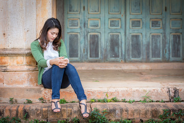 Depressed women. Asian beautiful girl sits sadly on the cement floor in ancient houses.