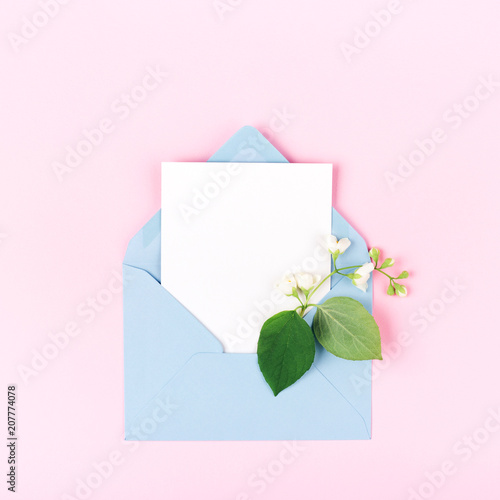 Mockup with blue envelope and jasmine flower on pink background. Minimal styl...