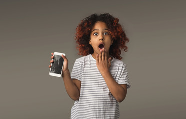 Black little girl with crashed mobile on gray background