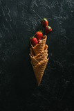 Fototapeta Nowy Jork - Ripe strawberries in stacked waffle cones on dark background