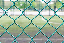 Green Wire Fence And Football Field On Background