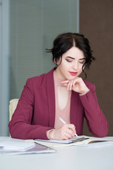 Wall Mural - serious confident busy young business woman at work writing. casual stylish formal wear