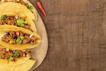 Wall Mural - Overhead closeup photo of Mexican tacos with pulled meat, avocado, chili peppers, cilantro, with copy space