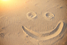 A Smiley Face Drawing On A Sand