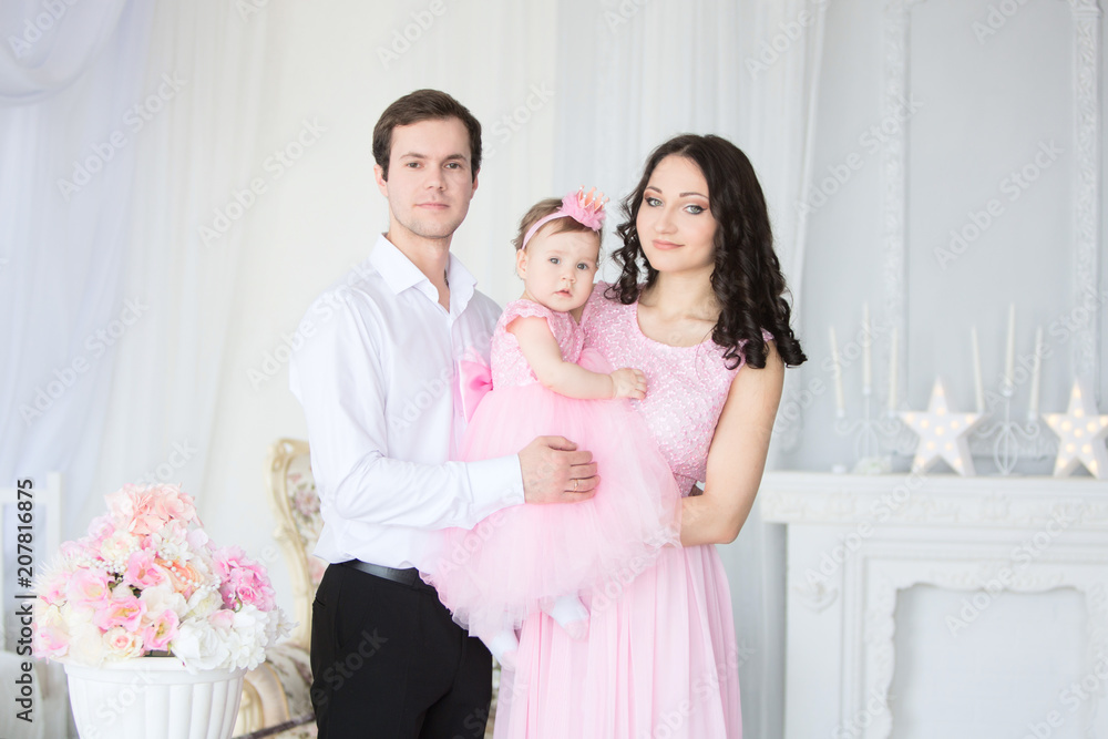 happy family father, mother and one-year-old child girl in pink dresses on birthday party. Stock Photo | Adobe Stock happy family father, mother and one-year-old child girl in pink dresses on birthday party. Stock Photo | Adobe Stock