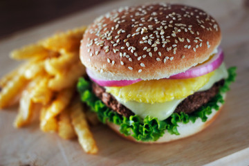 A served hamburger with a pineapple topping in the middle.  