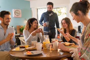 Wall Mural - Group of multi-ethnic friends gathered around a table for breakf